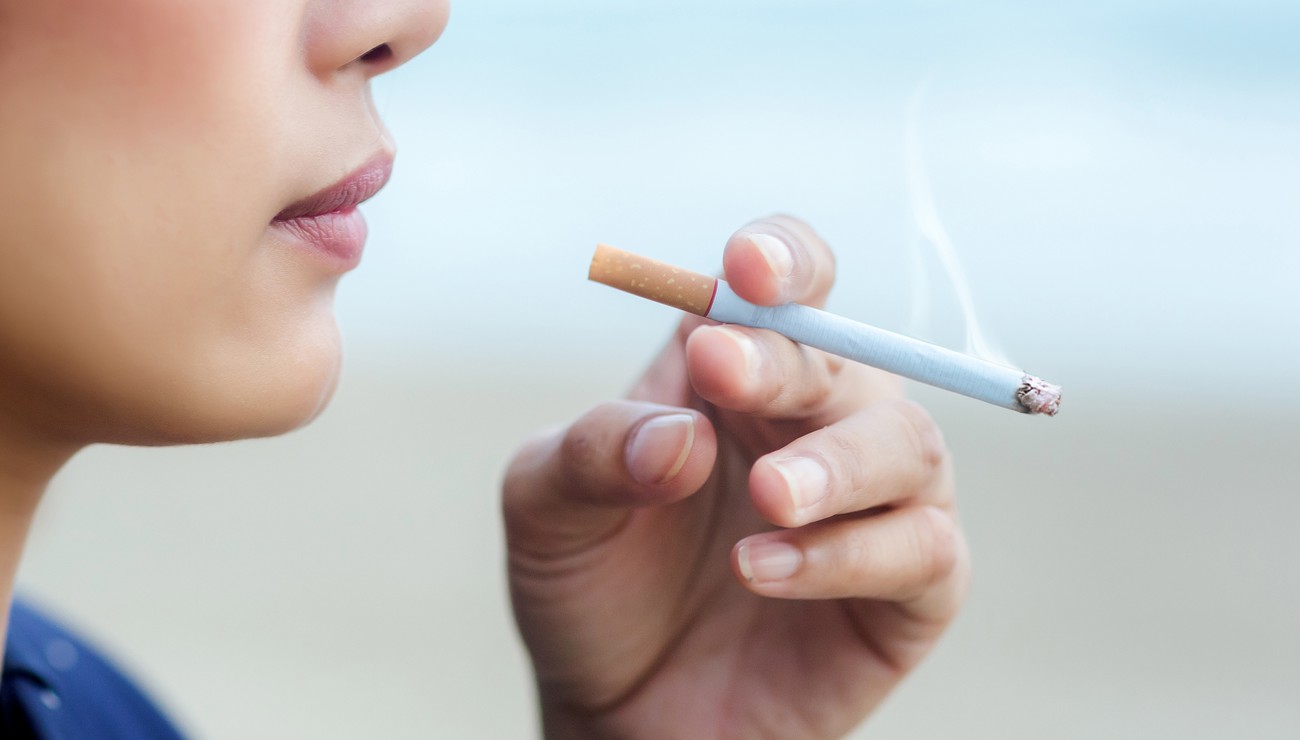 asian woman smoking a cigarette, selective focus cigarette